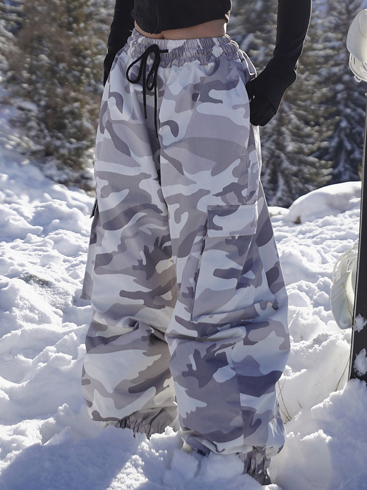 Gray camo baggy snow pants for women, standing in fresh snow