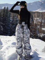 Woman in gray camo baggy snowboard pants and black jacket on the mountain