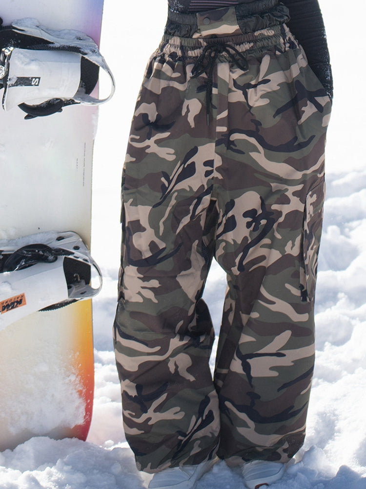 Army green camo baggy snow pants with a snowboard, front view