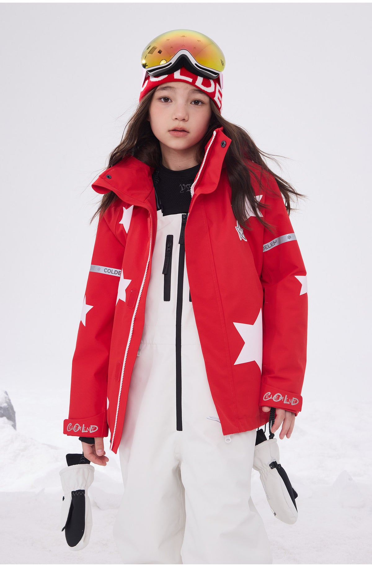 Child wearing red star print waterproof ski jacket and goggles in snow