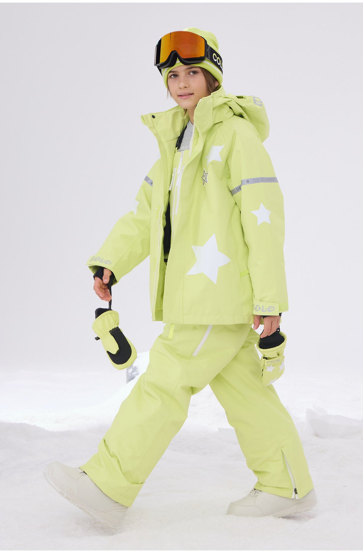 Kid in lime green star print ski jacket walking in the snow