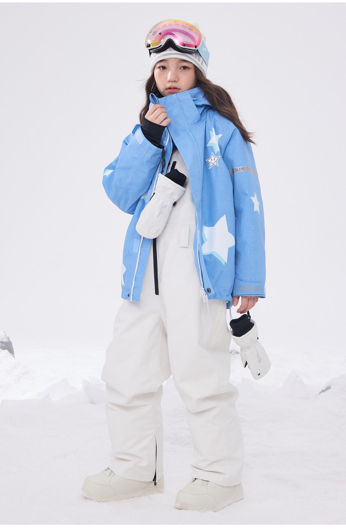 Child wearing light blue 3L ski jacket with white snow bibs