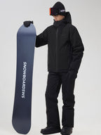 Men's black ski jacket and snow pants set, holding a snowboard
